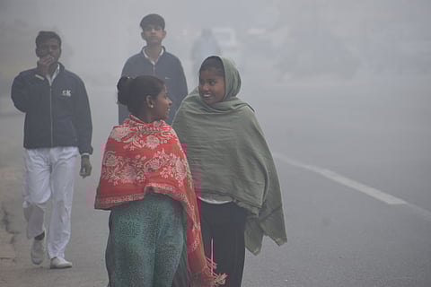People walk through dense winter fog in Delhi