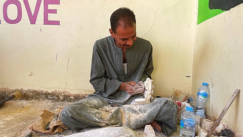 Local artisan Ahmed Mohammed carving a folk figure from alabaster stone