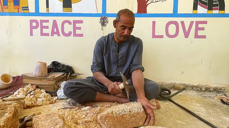 Ramadan Komsan is hammering a large calcite chunk