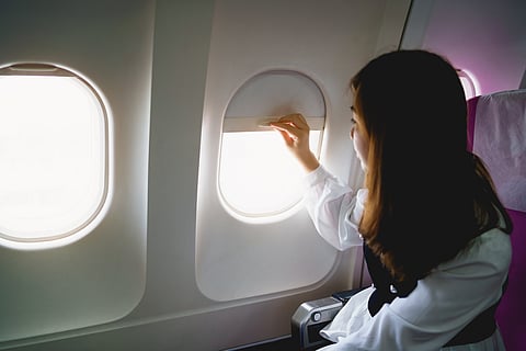 A passenger looks out of an aircraft window during a flight