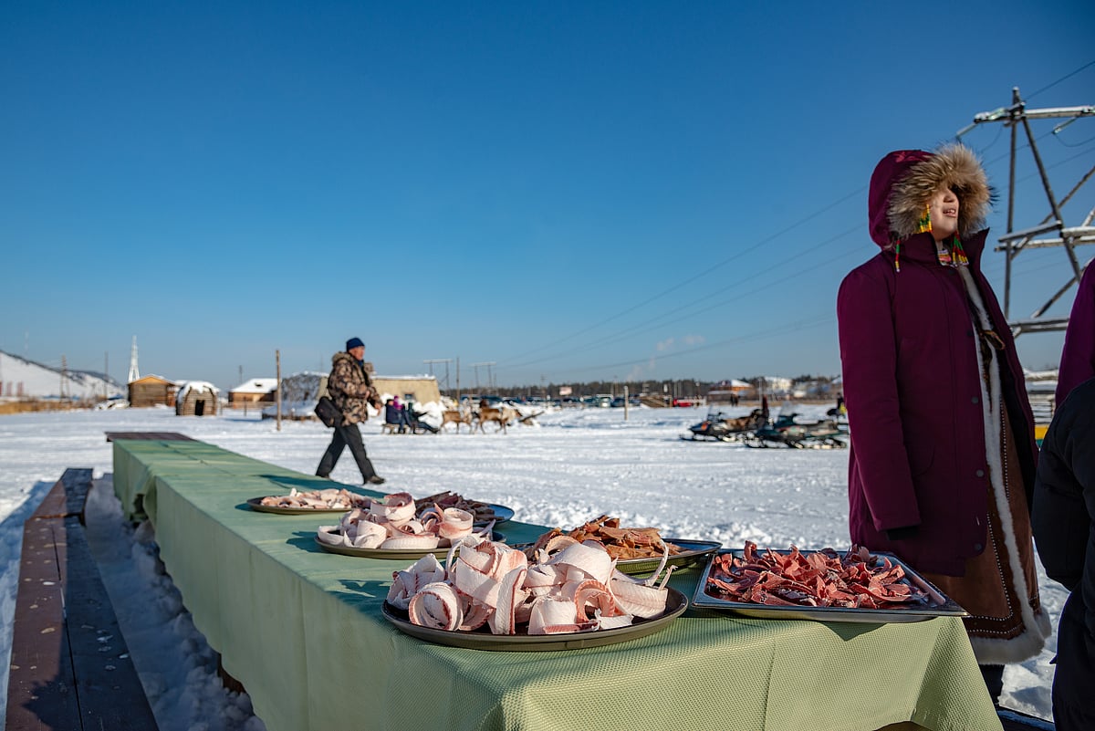 A Yakut woman next to a table with traditional food