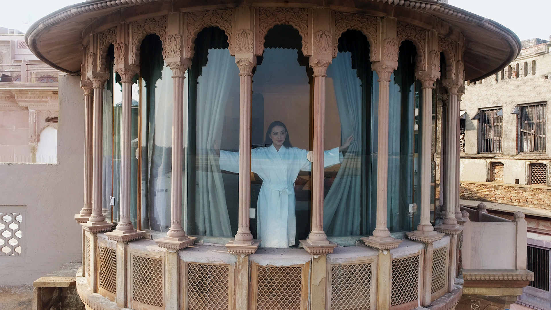 A woman looks out from her Varuna room at Brijrama Palace