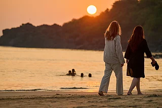 Shutterstock : Two women take a stroll along a Goa beach at sunset