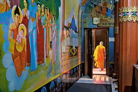 A monk walks past brightly painted walls inside the Society
