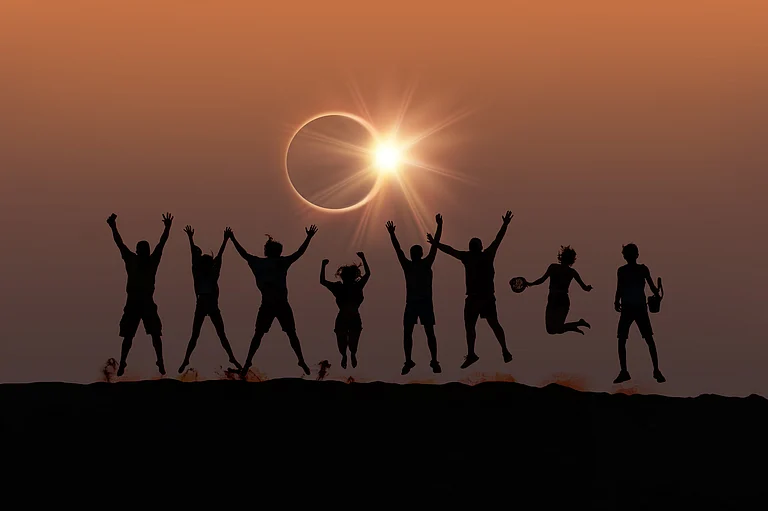 Friends captured in silhouette during a solar eclipse - Shutterstock
