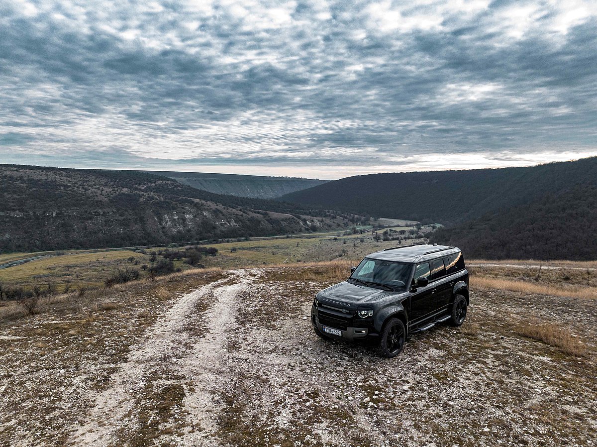 A black Land Rover Defender on top of a hill 