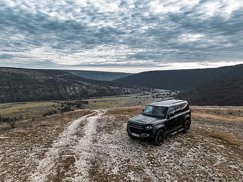 A black Land Rover Defender on top of a hill 