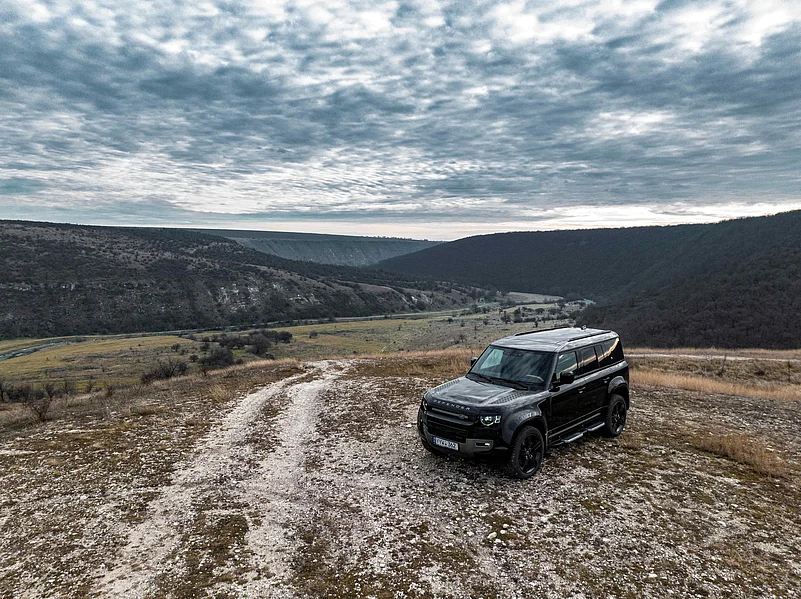 A black Land Rover Defender on top of a hill