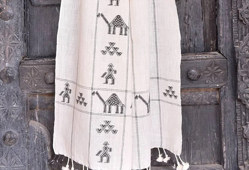 The cloth they produce — shawls, sarees, blankets — is instantly recognisable: bold geometric patterns raised off a plain-woven surface, each motif built thread by thread from within the fabric itself.