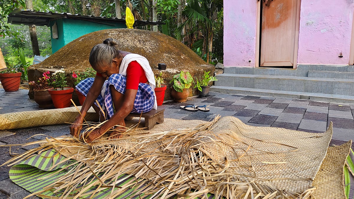 An elderly woman weaving a mat