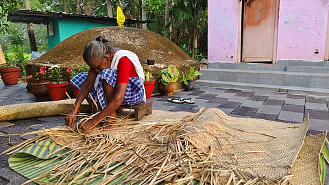An elderly woman weaving a mat
