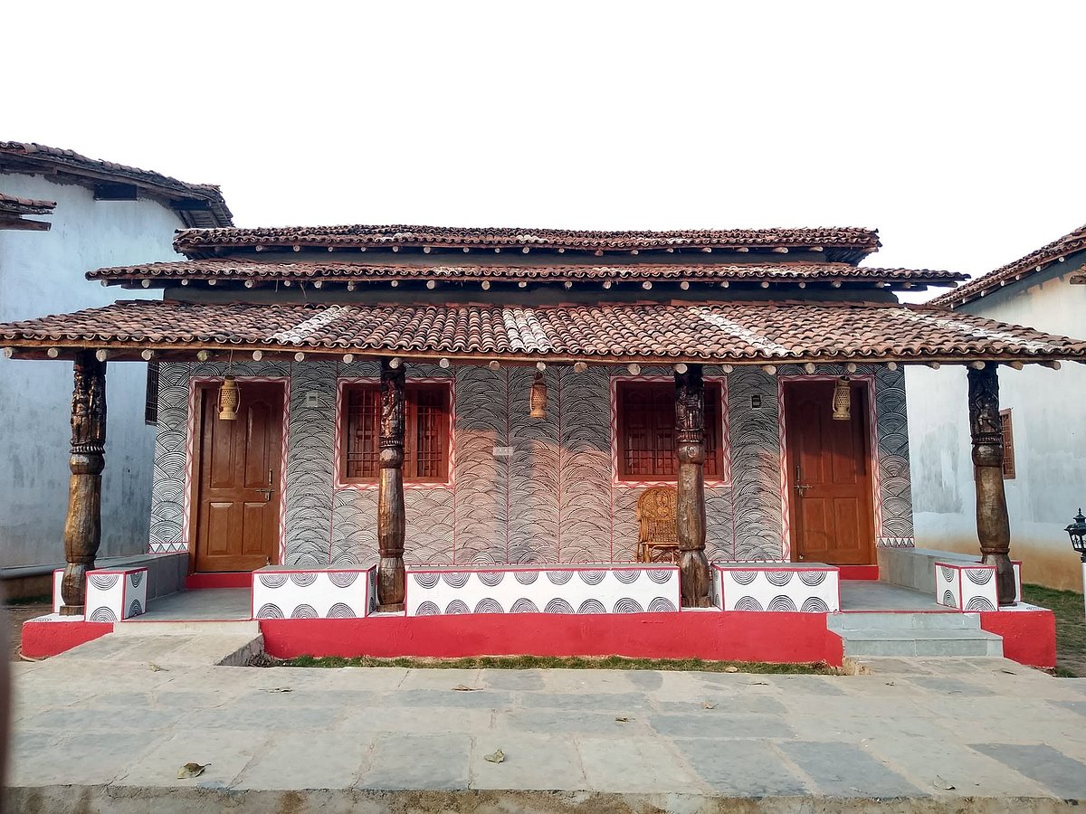 Oraon artist Sumanti Bhagat stands in front of a house adorned with her artwork, which draws on indigenous motifs, rituals and cultural traditions.