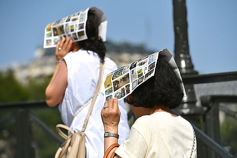 Tourists shield themselves from the sun during extreme heat in Paris