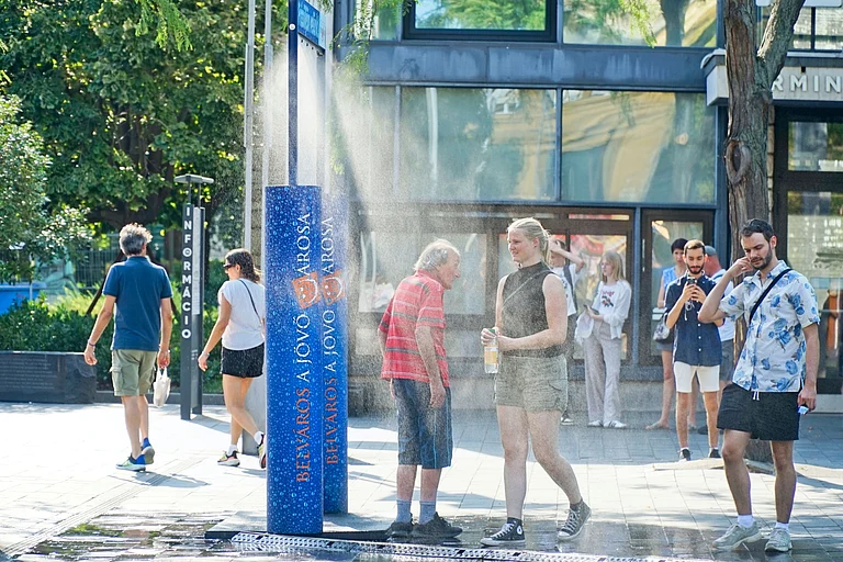 People cool off at public water sprayers during Budapest's summer heatwave - Shutterstock