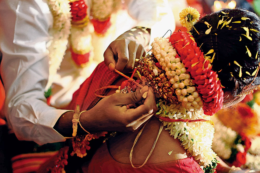 The groom ties the thali (mangalsutra) around the brides neck during a Tamil wedding