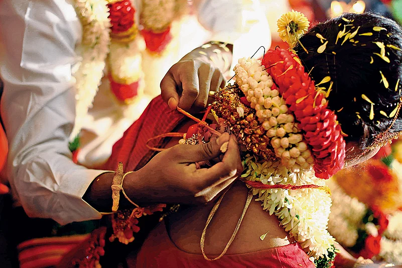 The groom ties the thali (mangalsutra) around the brides neck during a Tamil wedding