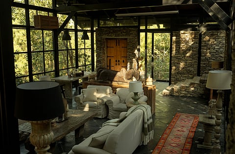 The lounge at The Sen, with stone walls, glass, wood and forest views