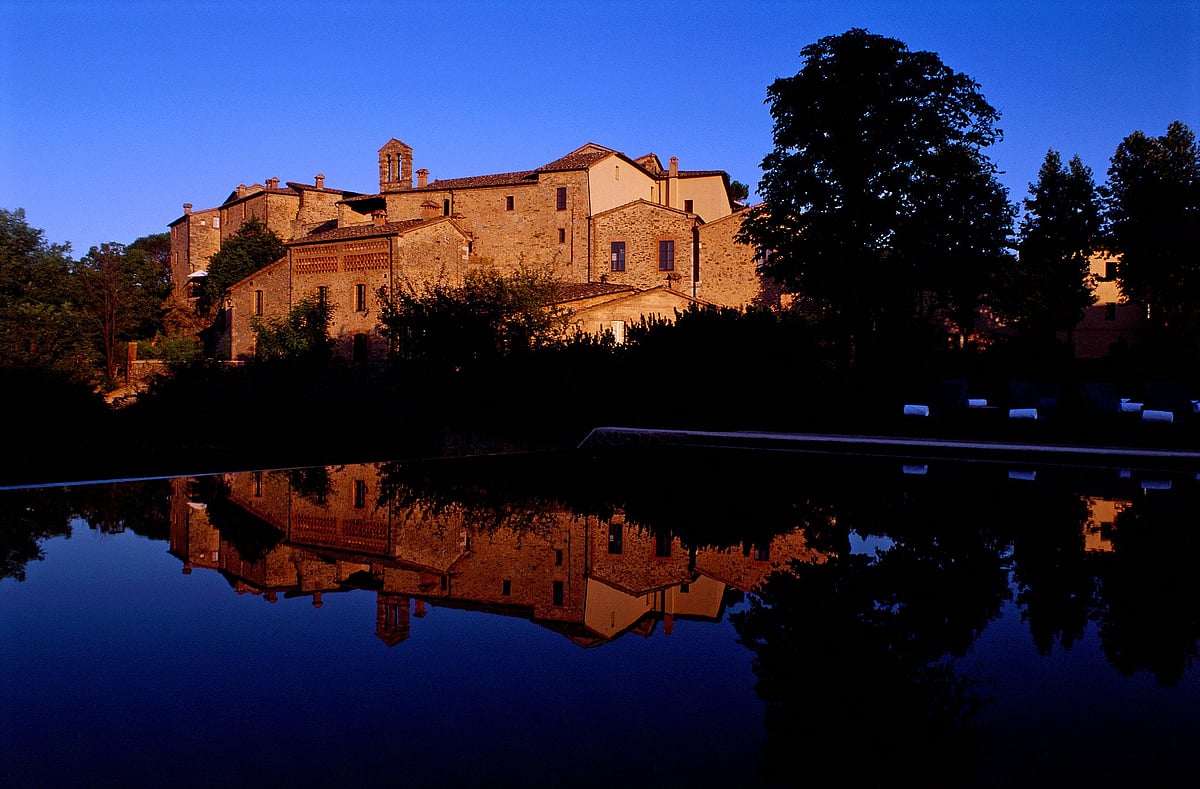 A restored medieval village and monastery surrounded by the rolling hills of Tuscany
