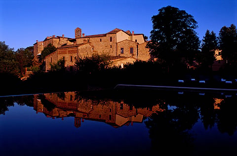 A restored medieval village and monastery surrounded by the rolling hills of Tuscany