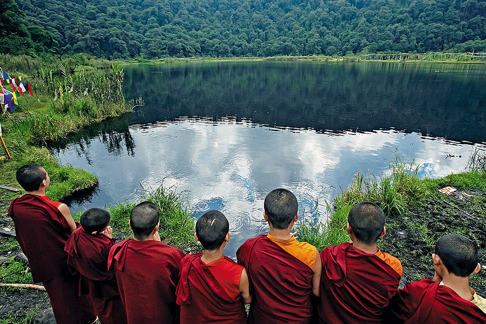 Shutterstock : Monks praying beside Khecheopalri Lake in Sikkim