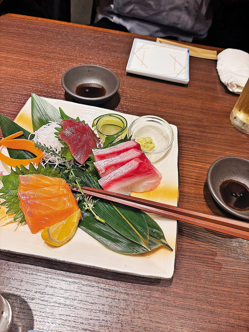 A plate of salmon, tuna and hamachi sashimi with daikon, wasabi and soy sauce