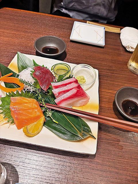A plate of salmon, tuna and hamachi sashimi with daikon, wasabi and soy sauce