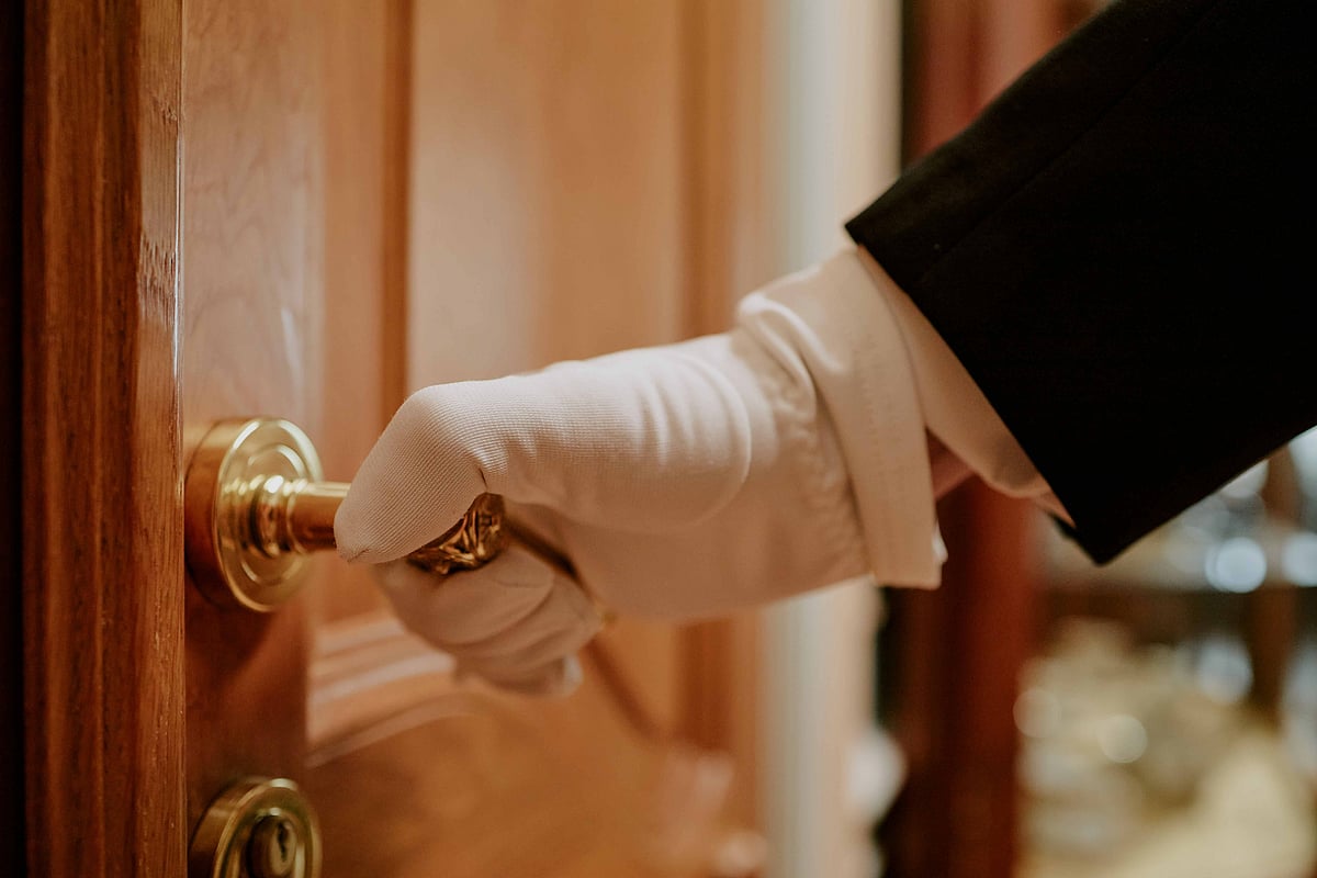 A hotel butler attends to guests’ needs with discretion and care