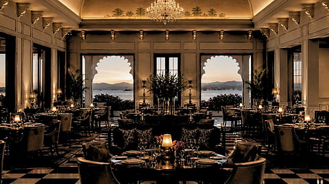 A dining setting illuminated by chandeliers and framed by the lake