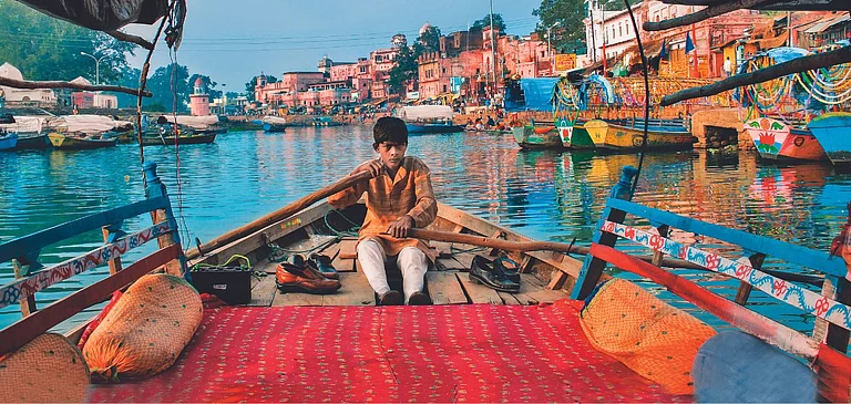 A boy sailing his boat on the Mandakini River in Chitrakoot, Madhya Pradesh - Shutterstock