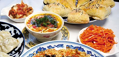 An Uzbeki spread with manti dumplings, shurpa, somsa, rice plov, and pickled vegetables