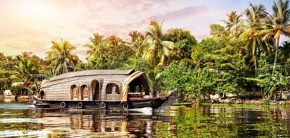House boat in backwaters near palms at sunrise sky in Alappuzha, Kerala