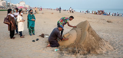 A local artist creates sand art on the beach in Puri.