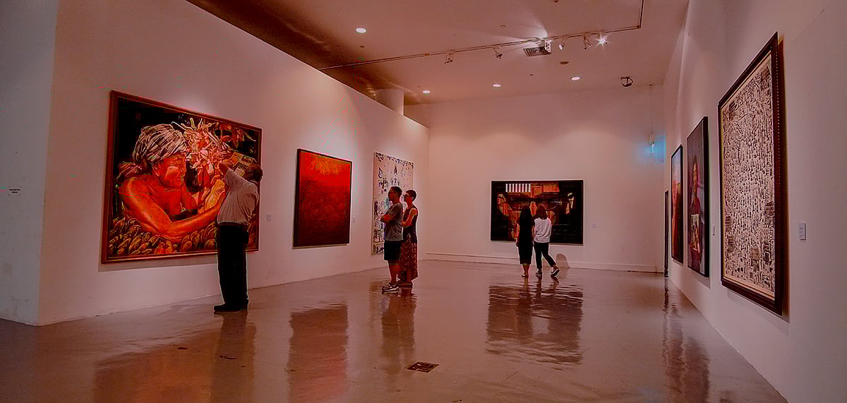 People looking at the paintings in the art gallery.