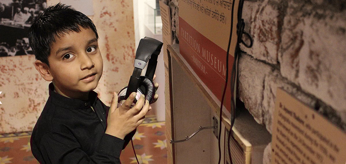 A child listening to an audio-visual presentation at the Partition Museum 