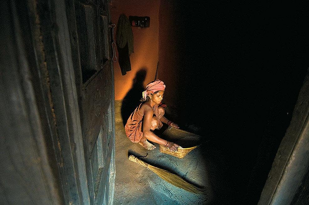 A young Dongria Kondh woman threshes rice to glean the grain from the chaff