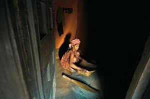 A young Dongria Kondh woman threshes rice to glean the grain from the chaff
