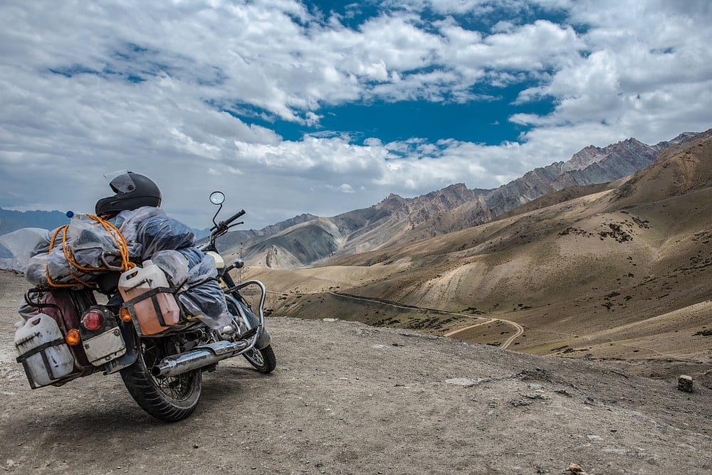 Scenic view of road by landscape with mountain, road and blue sky seen through motor bike,