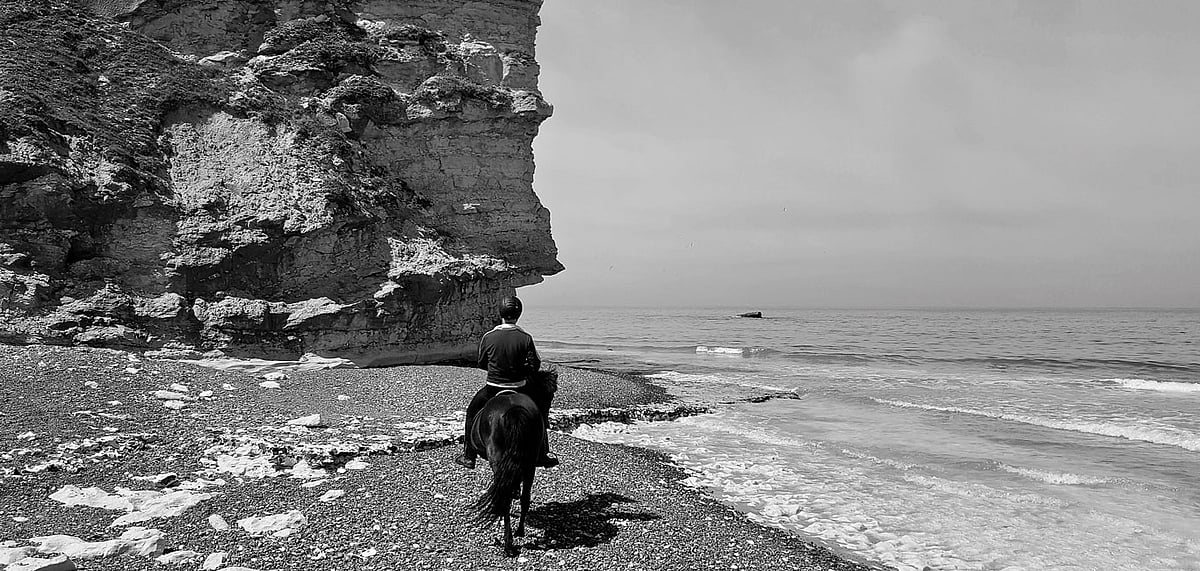 To pass below the overhang of the cliff, we had to dismount and lead our frightened horses across during the few seconds reprieve between two waves