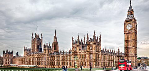 The Houses of Parliament and the Big Ben clock tower in London with an iconic bus in frame