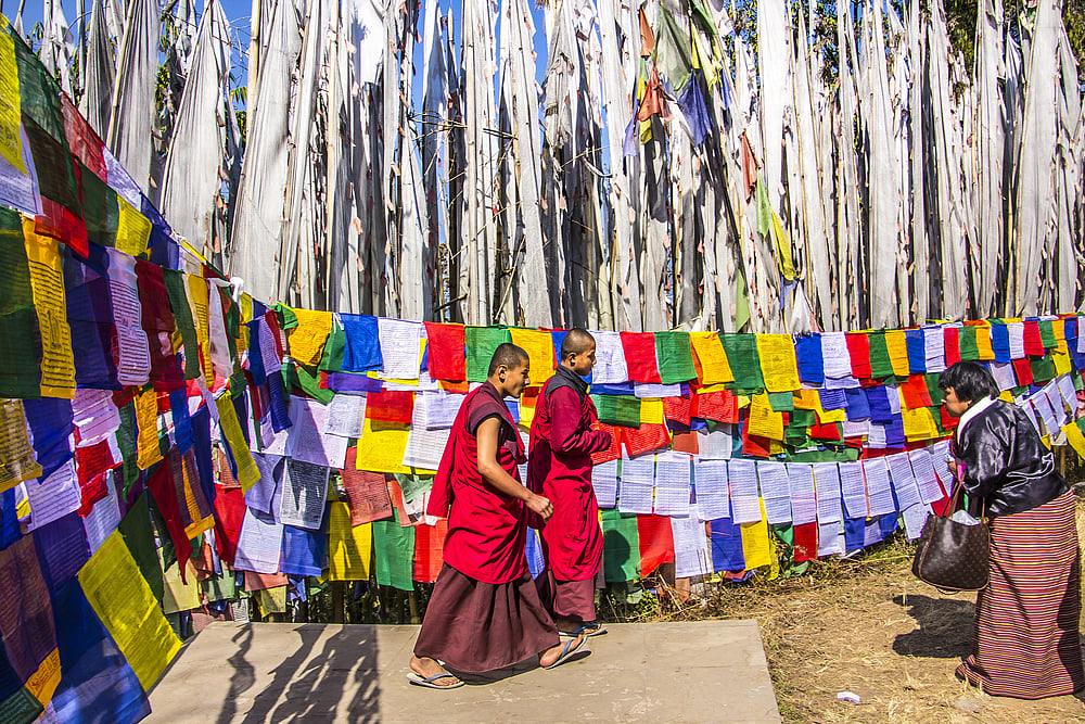 Buddhist monks walk past prayer flags at the Tashiding monastery in Sikkim