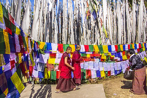 Buddhist monks walk past prayer flags at the Tashiding monastery in Sikkim
