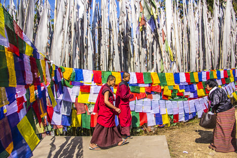 Buddhist monks walk past prayer flags at the Tashiding monastery in Sikkim