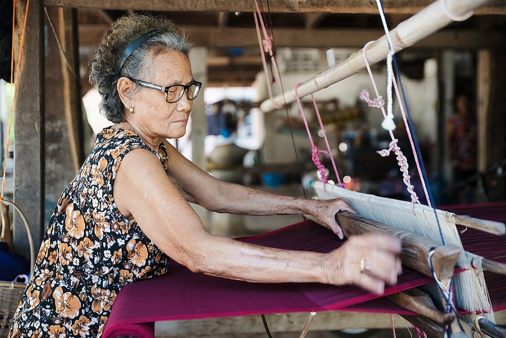 Isan Thai silk weaving on a wooden loom in Kalasin, Thailand.