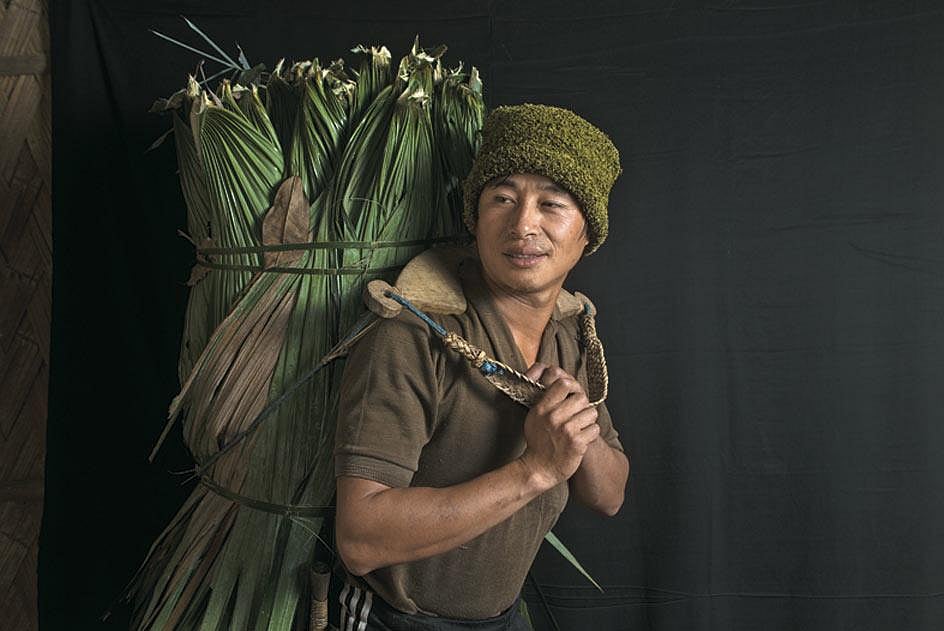 A Lisu man carrying leaves from the forest to help construct a neighbours house in Nibudi.
