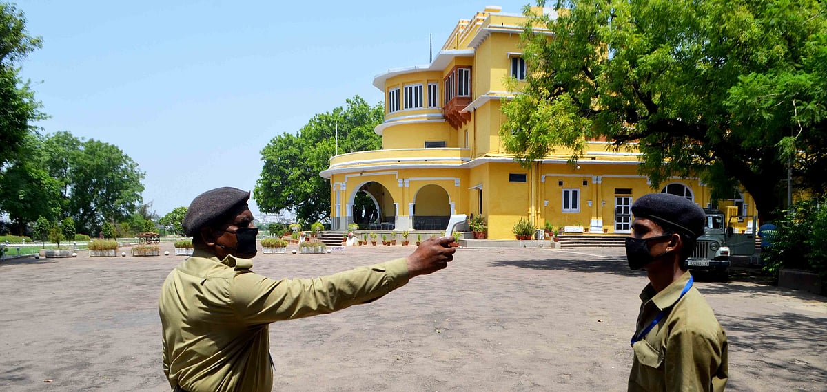A security guard thermal screens a staff member as he returns from the market at Brijraj Bhawan Palace Hotel 