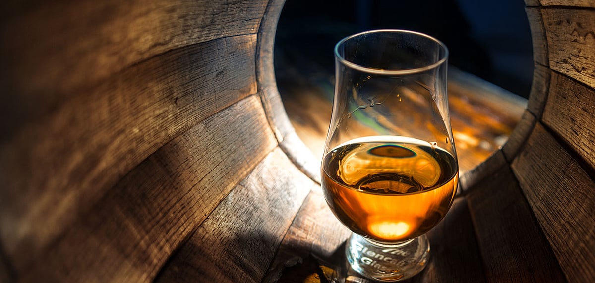 A glass of whiskey in an oak barrel