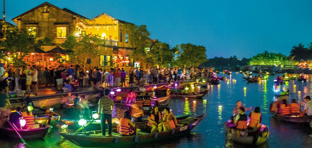Boats joining the twinkling waters of the Thu Bon river after sunset 