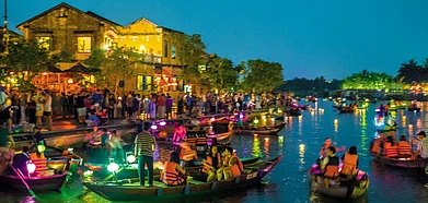 Boats joining the twinkling waters of the Thu Bon river after sunset