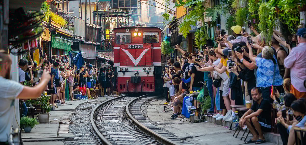 Tourists taking pictures of a train passing through the narrow street in the Hanoi Old Quarter