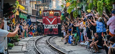 Tourists taking pictures of a train passing through the narrow street in the Hanoi Old Quarter